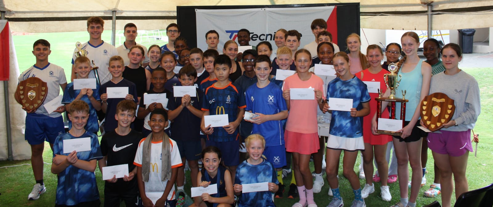 Prize-winners at the 2026 Tecnifibre Bloem Junior Open lined up under the marquee with their certificates and trophies