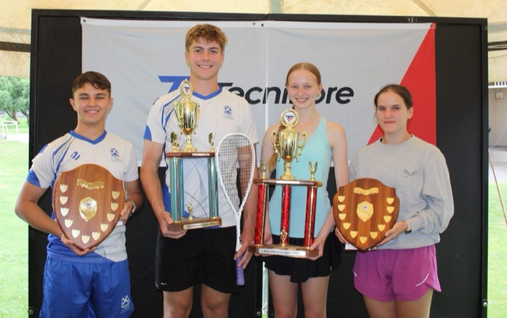 Four junior trophy winners with their shields and cups in front of the Tecnifibre backdrop